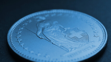 1 Swiss Franc coin closeup. Blue tinted background or wallpaper about economy, business or swissy....