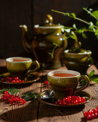 Tea in the vintage green set with red currant on the wooden table