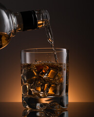 Glass of whisky with ice , a glass of whisky is poured from a bottle.