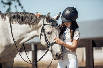 Young teenage girl equestrian showing love and care to her favorite horse. Dressage outfit