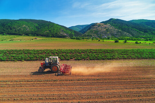 Tractor cultivating the ground in a agricultural field. Cultivate, agriculture and farming concept.