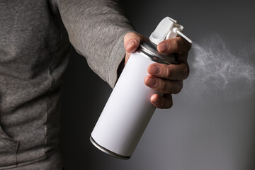 Person hand holding and spraying a blank aluminum spray can, aerosol can and small particles