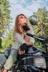 Middle age woman biker drives a motorcycle on a forest road, travels alone