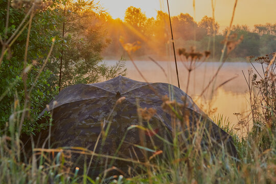 Fishing tent set in a gorgeous lake landscape image,  with the sun rising.