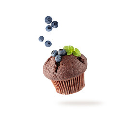 Fresh baked single chocolate muffin with blueberry berries and mint leaves flying on white...