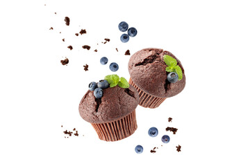 Fresh baked two chocolate muffins with blueberry berries, crumbs and mint leaves flying on white...