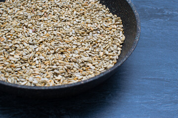 A pan with fried sunflower seeds on a ceramic countertop