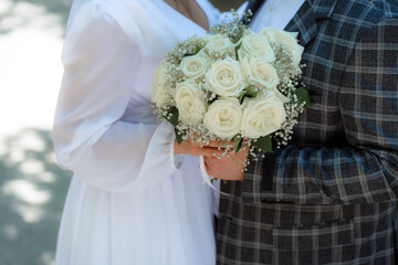 Wedding bouquet in the hands of the bride at the ceremony. Touching the hands of the bride and groom. Hugs of the newlyweds. Future married couple. The tenderness and beauty of the wedding ceremony.