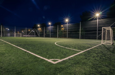 Fototapeta na wymiar Soccer field with artificial green grass near the school. Amateur football field. Summer evening