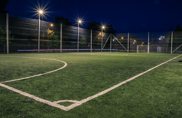 Plakat An amateur soccer field illuminated at night. A small football field lit by lanterns in the evening. Green football field illuminated at night. Soccer field in night with spotlight