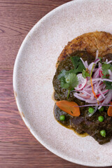 Carne asada con salsa de anticucho y criolla encima sobre tarta de papa