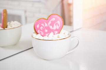 
Cup of tea with cake in shape of heart and marshmallow
