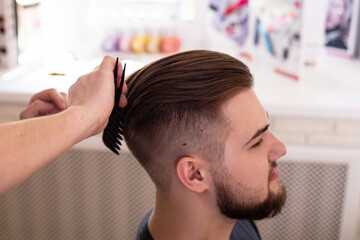 
Brunette man with stylish haircut on barbershop background

