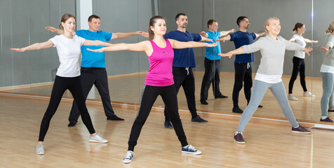 Group of adult people warming up before dance training in fitness center