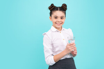 Teenage girl drinking water from glass on isolated blue background. Daily life health. Happy...