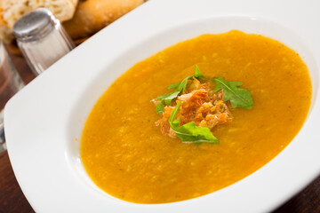 Healthy vegetable cream soup with fresh arugula leaves served in white plate ..
