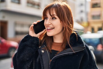 Young woman smiling confident talking on the smartphone at street