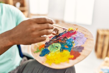 Hand of african american artist man mixing color on palette at art studio.