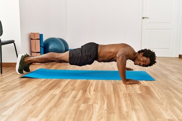 Fototapeta na wymiar Young african american man training push-ups at gym