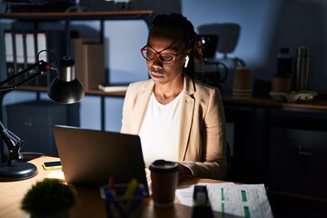 Beautiful black woman working at the office at night relaxed with serious expression on face. simple and natural looking at the camera.