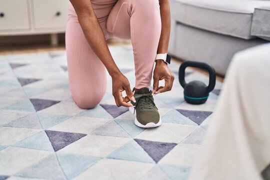 African american woman tying shoes at home
