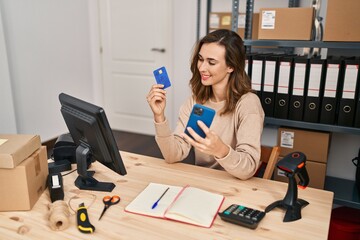 Young woman ecommerce business worker using smartphone and credit card at office