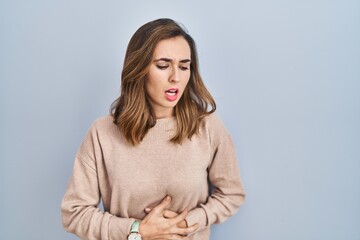 Obraz premium Young woman standing over isolated background with hand on stomach because indigestion, painful illness feeling unwell. ache concept.