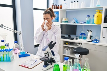 Young woman wearing scientist uniform using napkin at laboratory