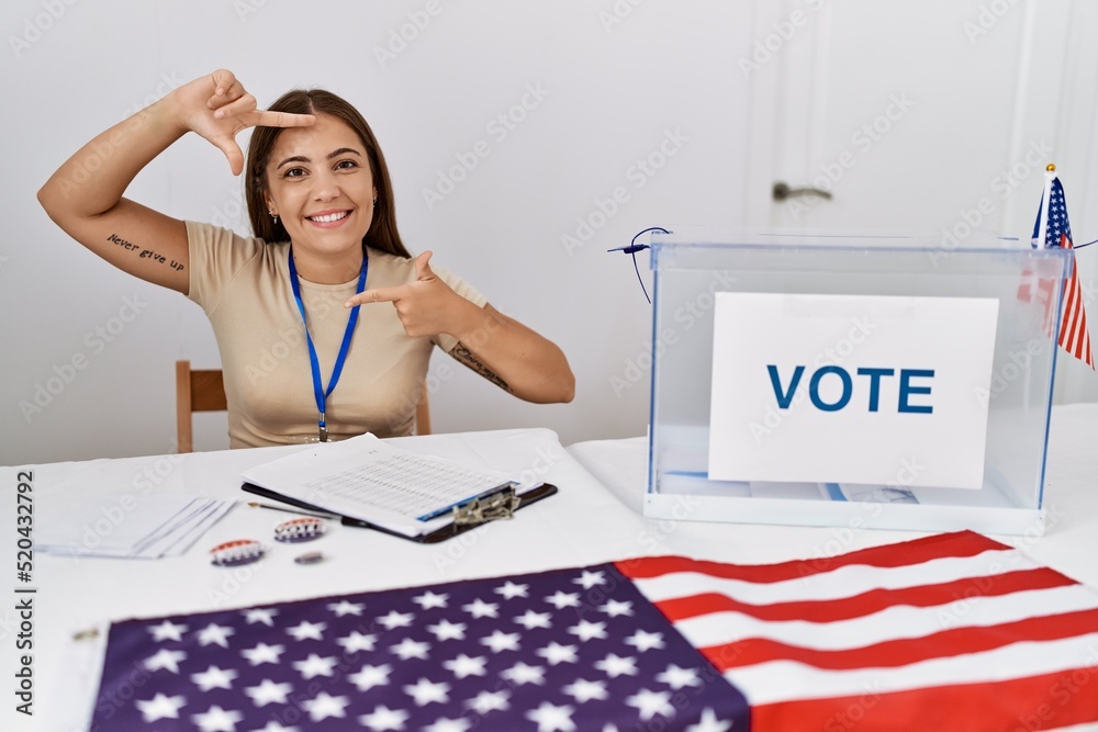 Sticker young brunette woman at political election sitting by ballot smiling making frame with hands and fin