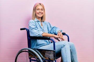 Beautiful blonde woman sitting on wheelchair with a happy and cool smile on face. lucky person.