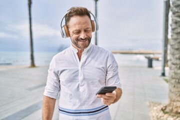 Middle age man using smartphone by the sea