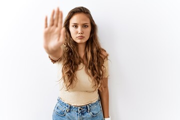 Obraz premium Beautiful hispanic woman standing over isolated while background doing stop sing with palm of the hand. warning expression with negative and serious gesture on the face.