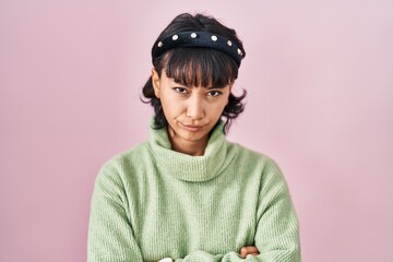 Young beautiful woman standing over pink background skeptic and nervous, disapproving expression on face with crossed arms. negative person.