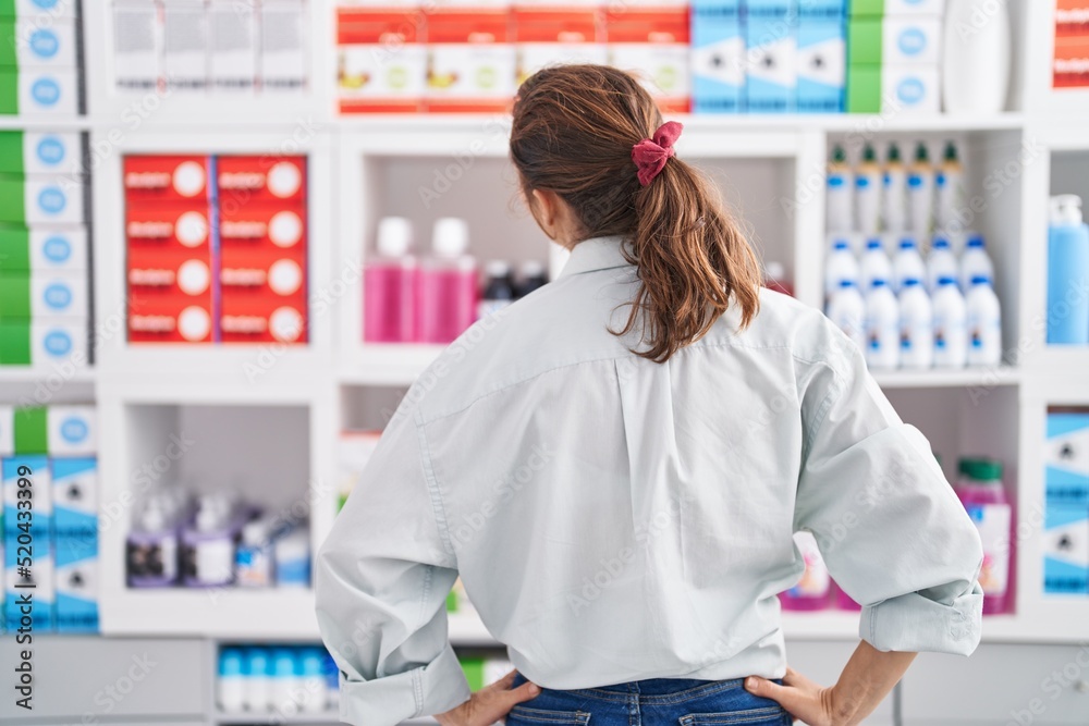 Poster Young woman customer standing on back view at pharmacy