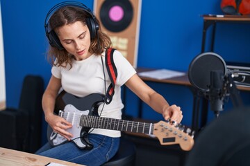 Fototapeta na wymiar Young woman artist playing electrical guitar at music studio