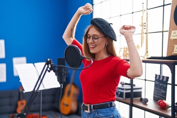 Young redhead woman artist singing song at music studio