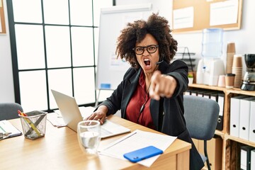 African american woman with afro hair working at the office wearing operator headset pointing displeased and frustrated to the camera, angry and furious with you
