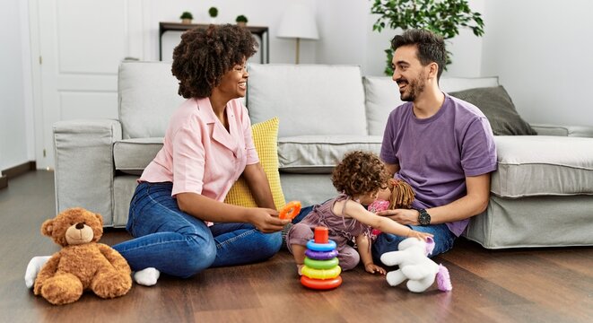 Couple and daughter smiling confident playing with toys sitting on the floor at home
