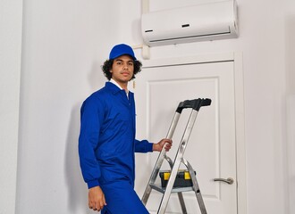 Hispanic man with curly hair working at home renovation thinking attitude and sober expression looking self confident