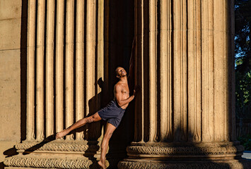 Emerging from the darkness to light and starting a new day.  Beautiful ballet dancer standing between two columns. 
