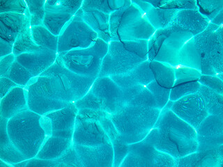 Turquoise surface of transparent sea water with sun glints