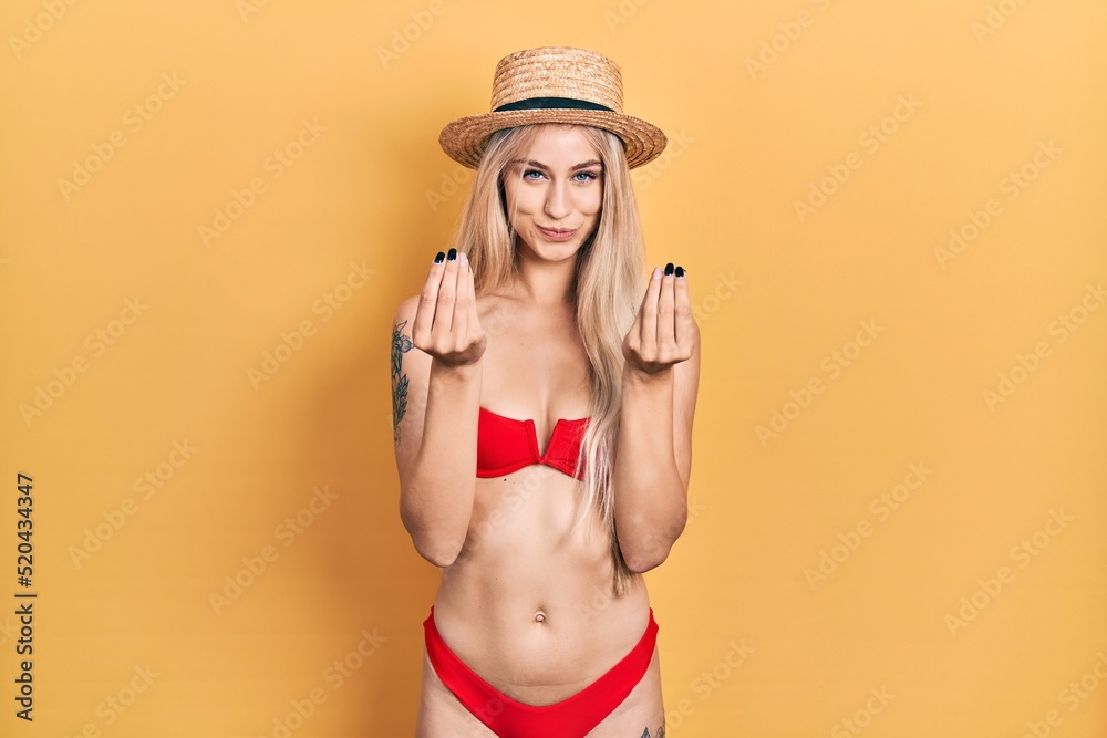 Canvas Prints young caucasian woman wearing bikini and summer hat doing money gesture with hands, asking for salar