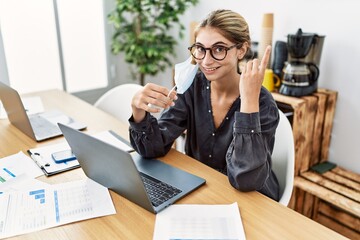 Young blonde woman working at the office wearing safety mask surprised with an idea or question pointing finger with happy face, number one