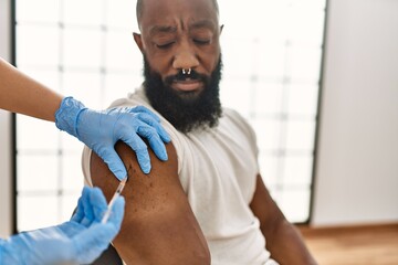 Hands of nurse woman injecting covid-19 vaccine to african amercian man at the clinic.
