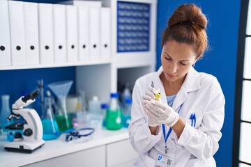 Fototapeta premium Young woman scientist writing on urine test tube at laboratory