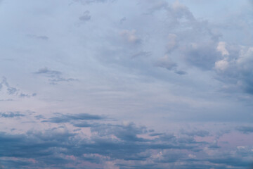 Fototapeta premium Beautiful high resolution sunset sky replacement background with a layer of low lying cumulus clouds with deep blue tones and textured upper clouds with hints of pink, and yellow hues.