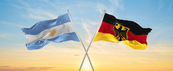 crossed national flags of Argentine and Germany flag waving in wind at cloudy sky. Symbolizing relationship, dialog, travelling between two countries. Copy space