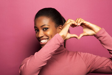 Young beautiful African American afro woman smiling in love doing heart symbol shape with hands