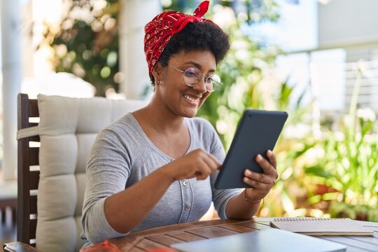 African american woman using touchpad sitting on table at home terrace