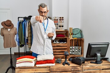 Middle age hispanic man working as manager at retail boutique punching fist to fight, aggressive...